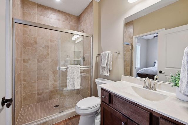 bathroom with toilet, a stall shower, wood finished floors, ensuite bath, and vanity