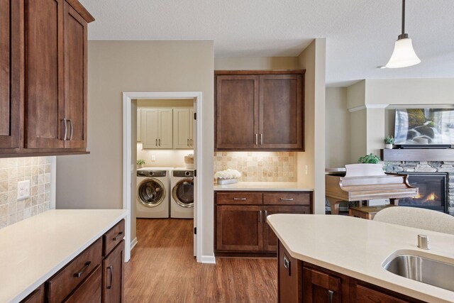 kitchen with light wood finished floors, separate washer and dryer, hanging light fixtures, light countertops, and backsplash