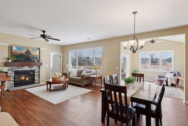 dining room with a wealth of natural light, a fireplace, and ceiling fan with notable chandelier