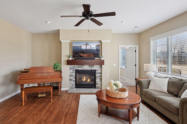 living room with baseboards, a stone fireplace, recessed lighting, wood finished floors, and a ceiling fan