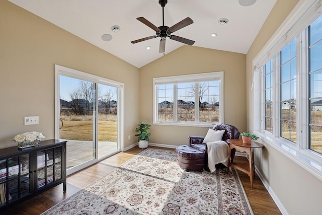 living area with a ceiling fan, wood finished floors, visible vents, baseboards, and vaulted ceiling