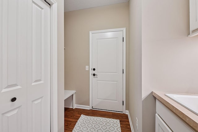 doorway to outside featuring baseboards and dark wood-style floors