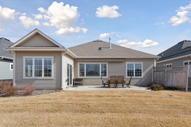 back of house featuring a yard, fence, a shingled roof, and a patio area