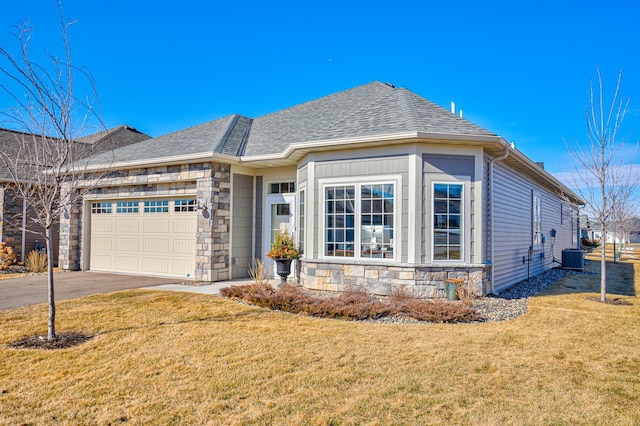 view of front of property featuring a garage, stone siding, aphalt driveway, and a front yard