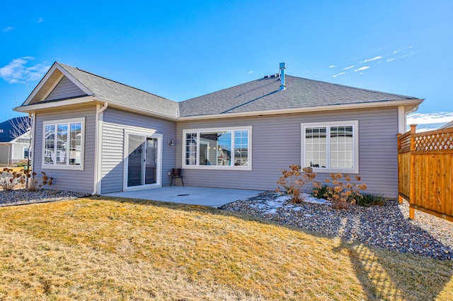 rear view of house featuring a shingled roof, fence, a lawn, and a patio