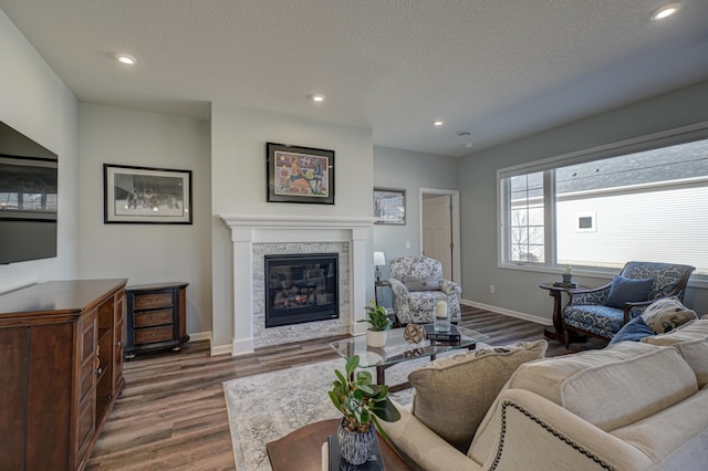 living area with dark wood-type flooring, recessed lighting, baseboards, and a tiled fireplace