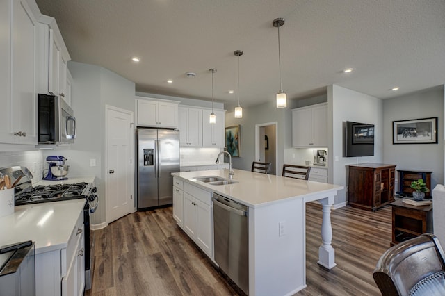 kitchen with dark wood finished floors, stainless steel appliances, a kitchen bar, white cabinetry, and a sink