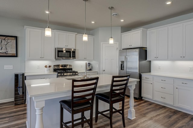 kitchen with light countertops, appliances with stainless steel finishes, dark wood-style flooring, and a sink