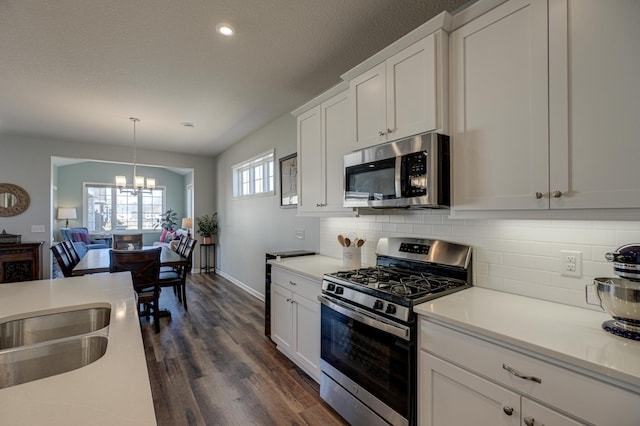 kitchen featuring dark wood-style flooring, tasteful backsplash, light countertops, appliances with stainless steel finishes, and white cabinetry