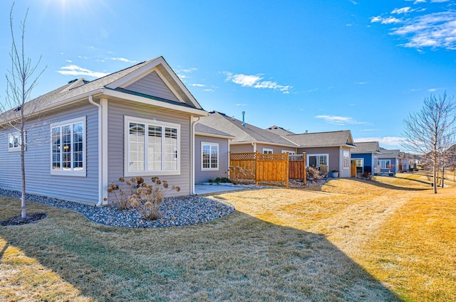 back of property with a lawn and fence