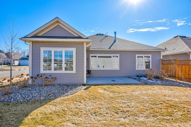 rear view of property with a shingled roof, a lawn, a patio area, and fence