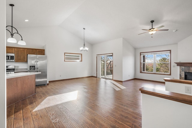 kitchen featuring stainless steel appliances, hanging light fixtures, lofted ceiling, dark wood-type flooring, and a tile fireplace