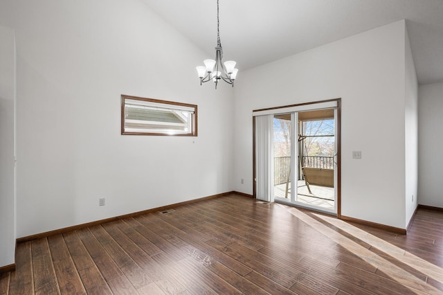 empty room with dark wood-type flooring, lofted ceiling, and a notable chandelier