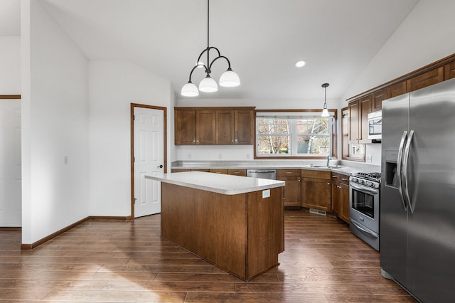 kitchen featuring stainless steel appliances, lofted ceiling, a center island, dark wood-type flooring, and pendant lighting