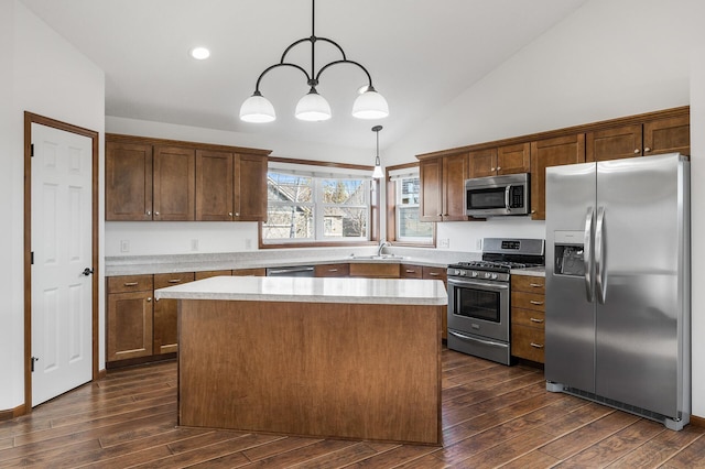 kitchen featuring stainless steel appliances, dark wood-type flooring, sink, a kitchen island, and decorative light fixtures