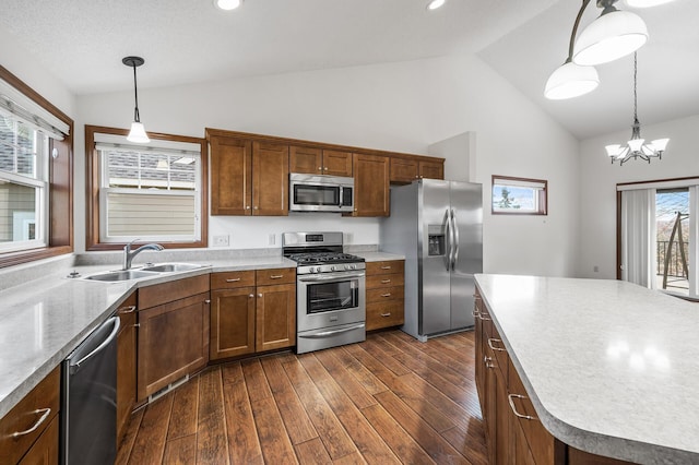 kitchen featuring stainless steel appliances, sink, an inviting chandelier, decorative light fixtures, and dark wood-type flooring