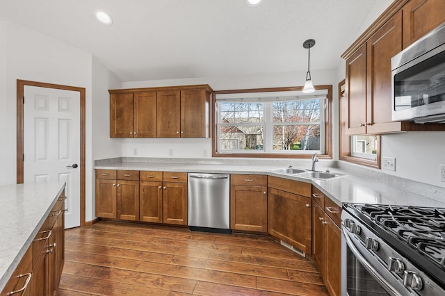 kitchen with dark hardwood / wood-style flooring, sink, appliances with stainless steel finishes, and decorative light fixtures