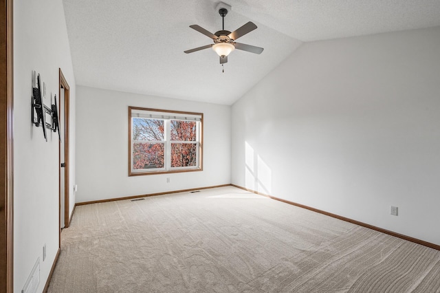 carpeted spare room with vaulted ceiling, ceiling fan, and a textured ceiling