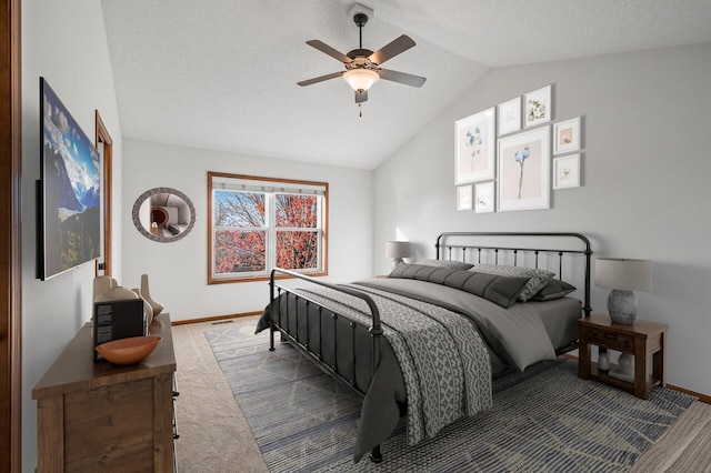 bedroom featuring carpet, vaulted ceiling, ceiling fan, and a textured ceiling