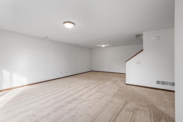 empty room with a textured ceiling and light carpet