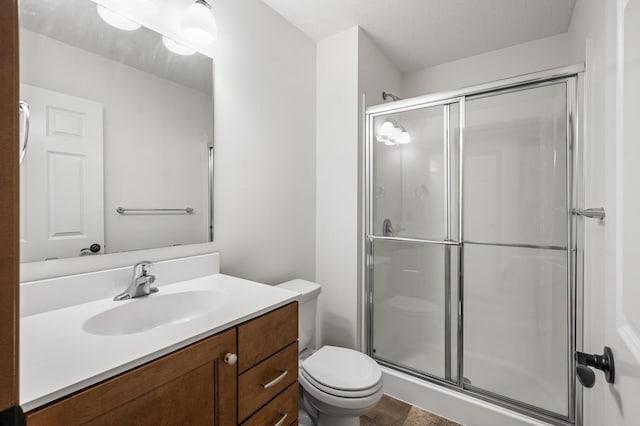 bathroom with vanity, toilet, an enclosed shower, and a textured ceiling