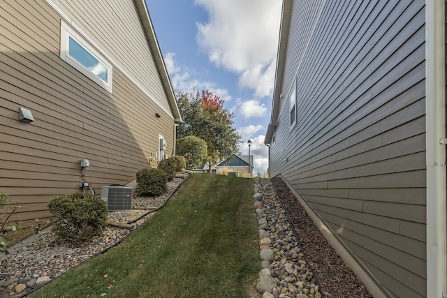 view of side of property with central AC unit and a lawn