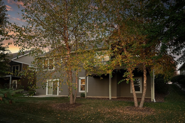 back house at dusk featuring a yard