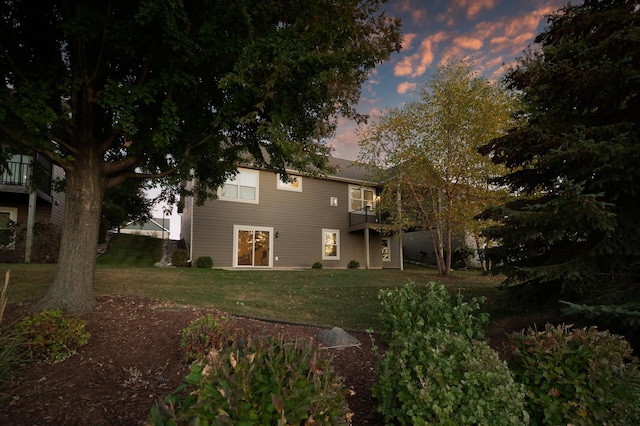 back house at dusk with a lawn