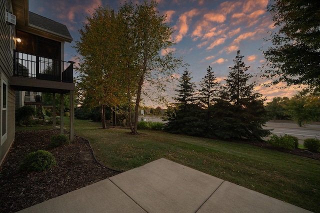 yard at dusk featuring a patio and a balcony