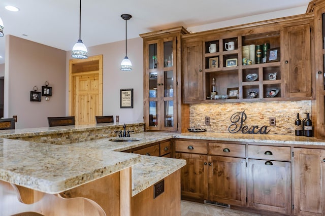 bar featuring light stone countertops, tasteful backsplash, sink, and decorative light fixtures