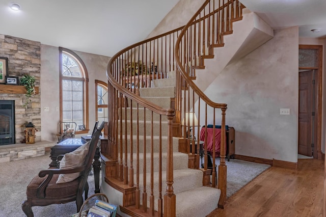 stairway featuring hardwood / wood-style flooring and a stone fireplace