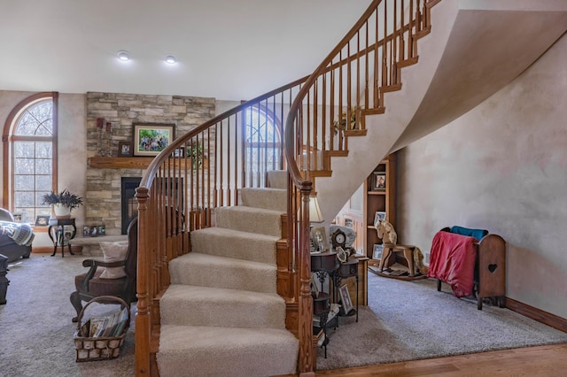 staircase with a stone fireplace and hardwood / wood-style flooring