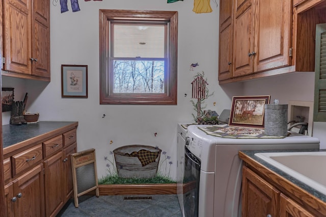 laundry room with washer and clothes dryer, dark tile patterned flooring, and cabinets