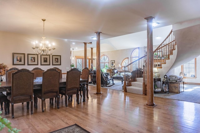 dining room featuring an inviting chandelier, decorative columns, hardwood / wood-style flooring, and plenty of natural light