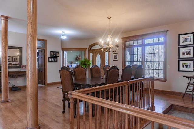 dining area featuring a notable chandelier, light wood-type flooring, and ornate columns