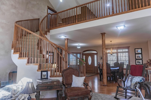 living room featuring an inviting chandelier, decorative columns, hardwood / wood-style floors, and a high ceiling