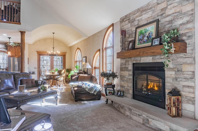 carpeted living room featuring vaulted ceiling, decorative columns, and a fireplace