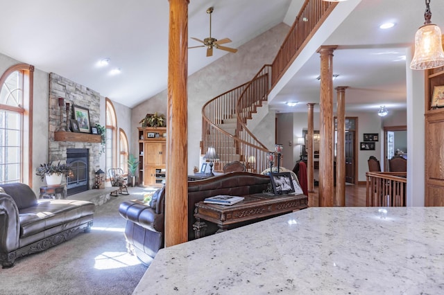 interior space featuring ceiling fan, high vaulted ceiling, carpet floors, a fireplace, and ornate columns