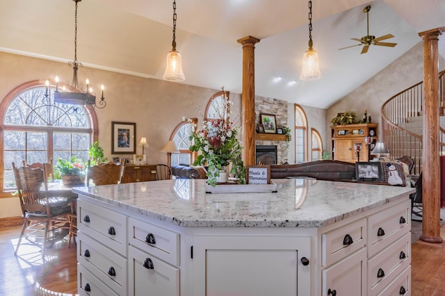 kitchen with pendant lighting, light wood-type flooring, a center island, white cabinets, and lofted ceiling