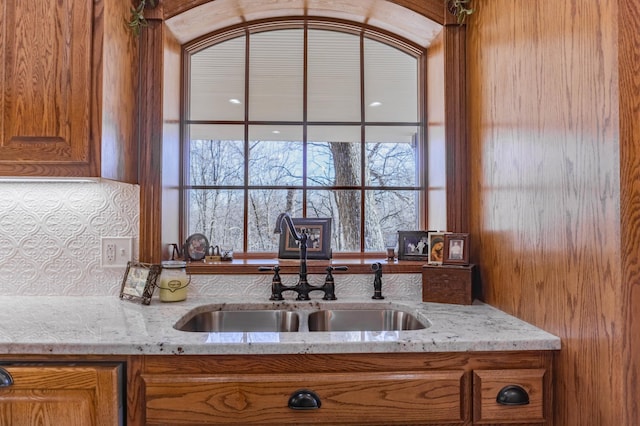 kitchen with light stone countertops, wood walls, and sink