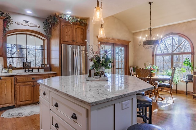 kitchen with light hardwood / wood-style floors, a center island, a notable chandelier, white cabinets, and stainless steel fridge