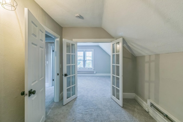 additional living space with a textured ceiling, lofted ceiling, french doors, light carpet, and baseboard heating