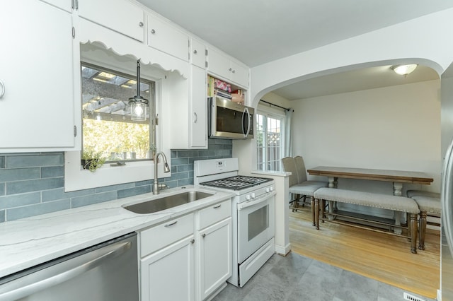 kitchen featuring light wood-type flooring, stainless steel appliances, white cabinets, sink, and backsplash