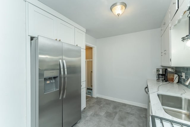 kitchen featuring light stone countertops, decorative backsplash, sink, white cabinetry, and stainless steel refrigerator with ice dispenser