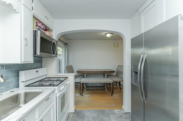 kitchen with white cabinets, appliances with stainless steel finishes, light hardwood / wood-style flooring, and sink