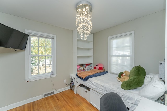 bedroom with a chandelier and light hardwood / wood-style floors