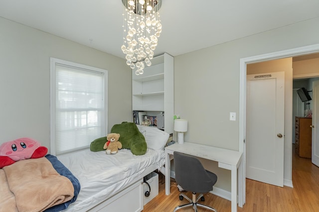 bedroom with light hardwood / wood-style floors and a chandelier