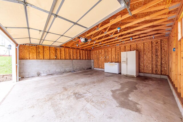 garage with white fridge, white refrigerator with ice dispenser, and a garage door opener