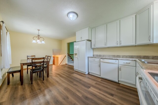 kitchen with white appliances, dark wood-type flooring, pendant lighting, an inviting chandelier, and white cabinets