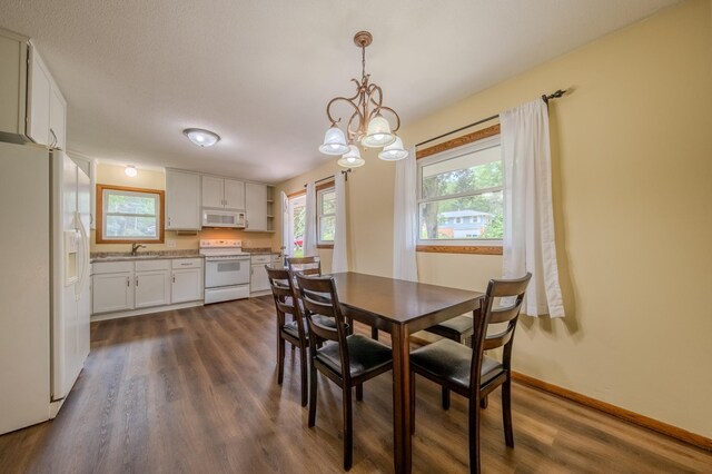 dining area featuring a textured ceiling, dark hardwood / wood-style floors, a notable chandelier, and sink